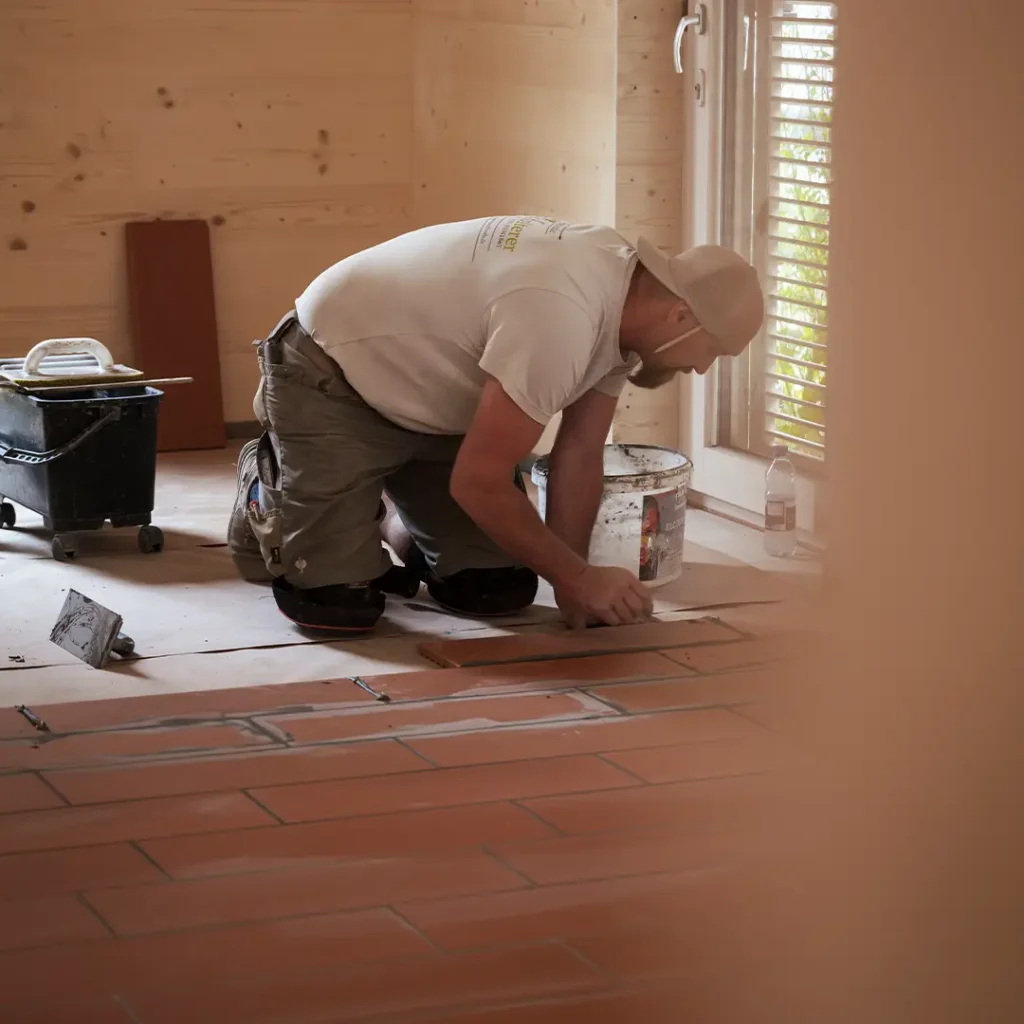 Ein Handwerker verlegt Estrichziegel in einem Raum.