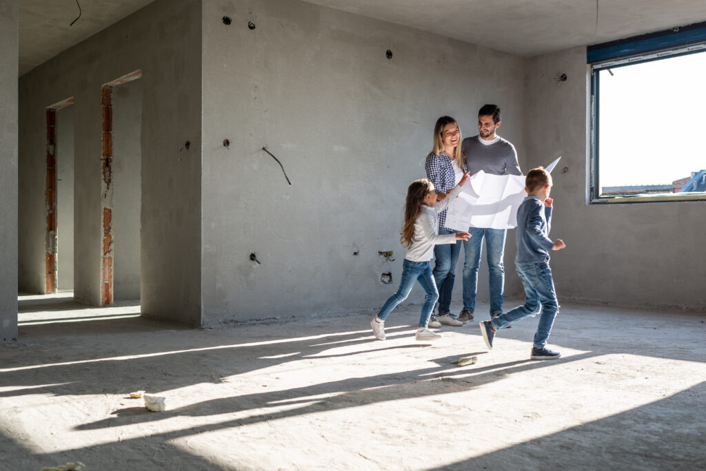 Junge Familie mit zwei Kindern auf Baustelle von Eigenheim