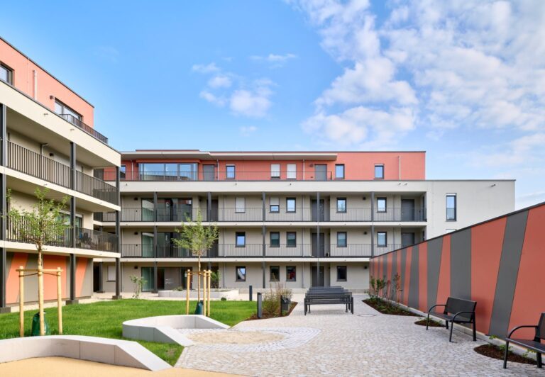 Der begrünte Innenhof mit verschiedenen Sitzgelegenheiten bietet den Bewohnern des Bürgerblocks GeWoGe mit dezentraler Lüftungslange in Landshut eine hohe und geschützte Aufenthaltsqualität.
