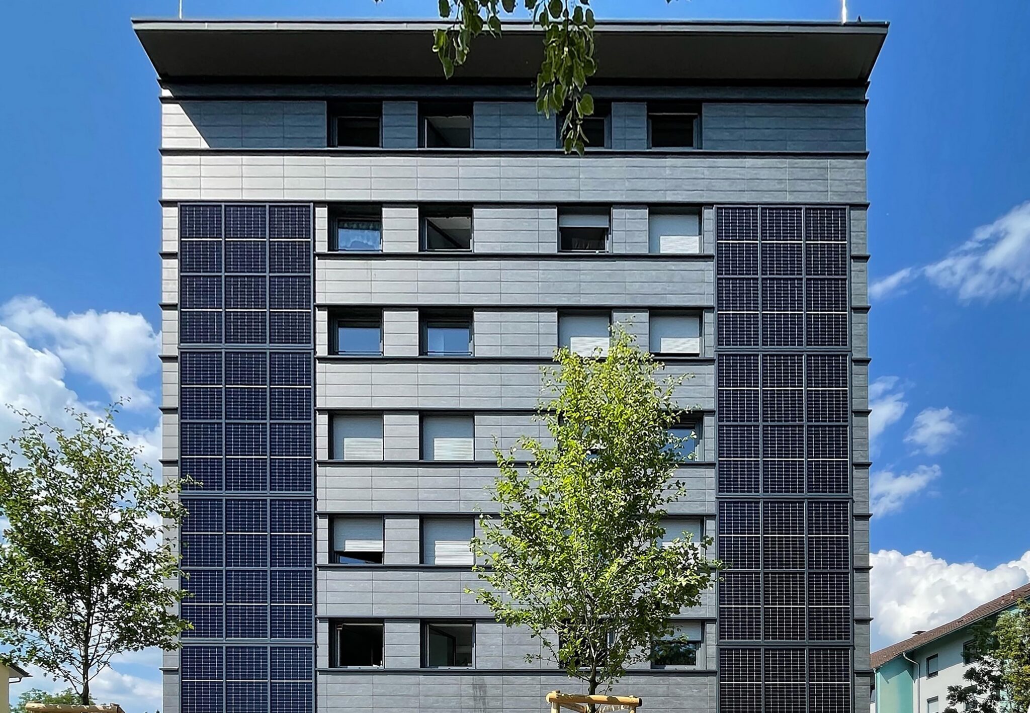 Saniertes Wohnheim in Lindau mit Fenster und Keramikelementen hinter einem Baum stehend