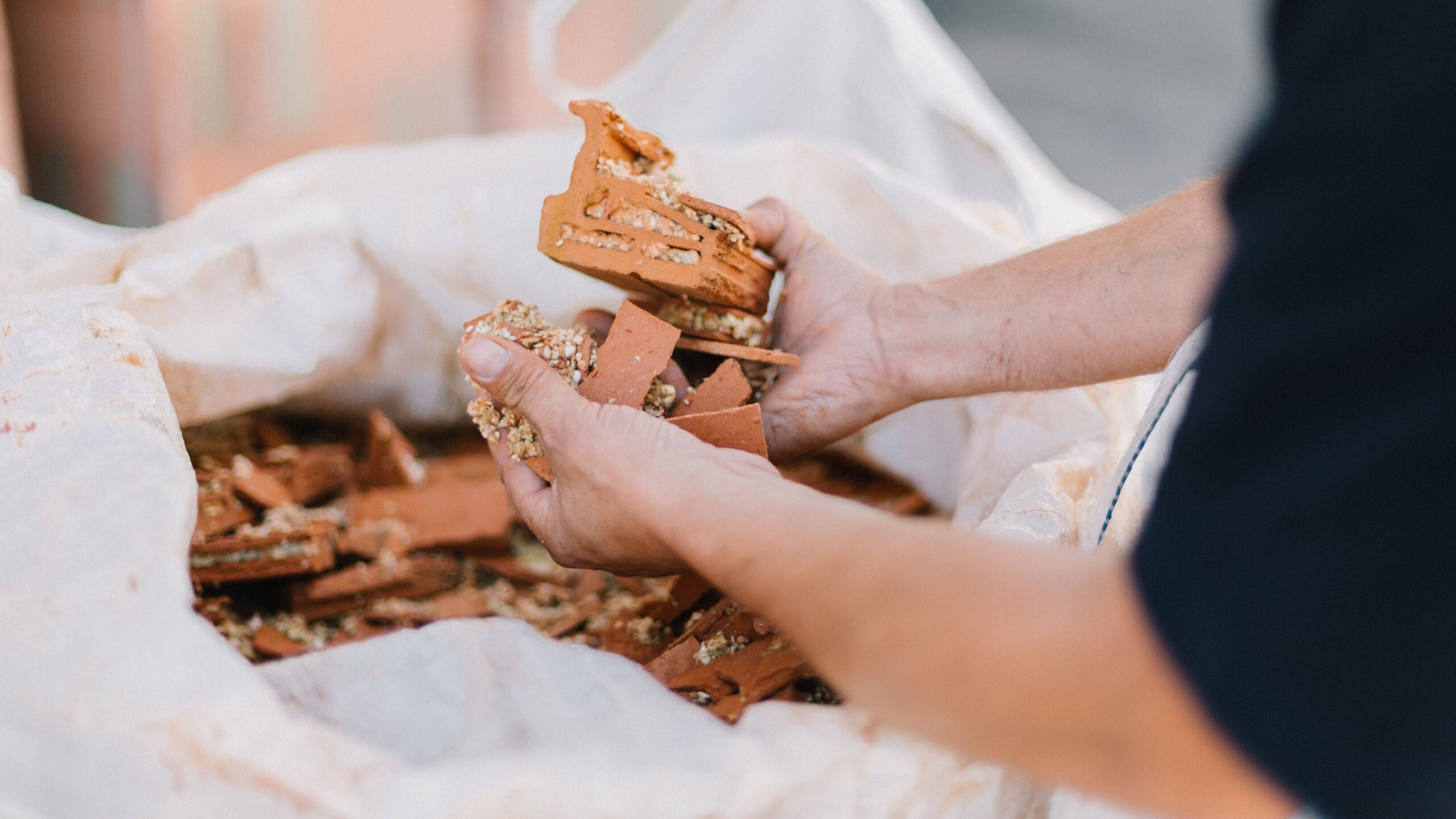 Ziegelteile für Kaltziegel in der Hand und in einem weißen Sack.