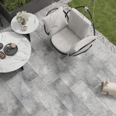 Außenbereich mit Lounge-Sessel, Tischen und Bobone Terrassenziegel in Grau.