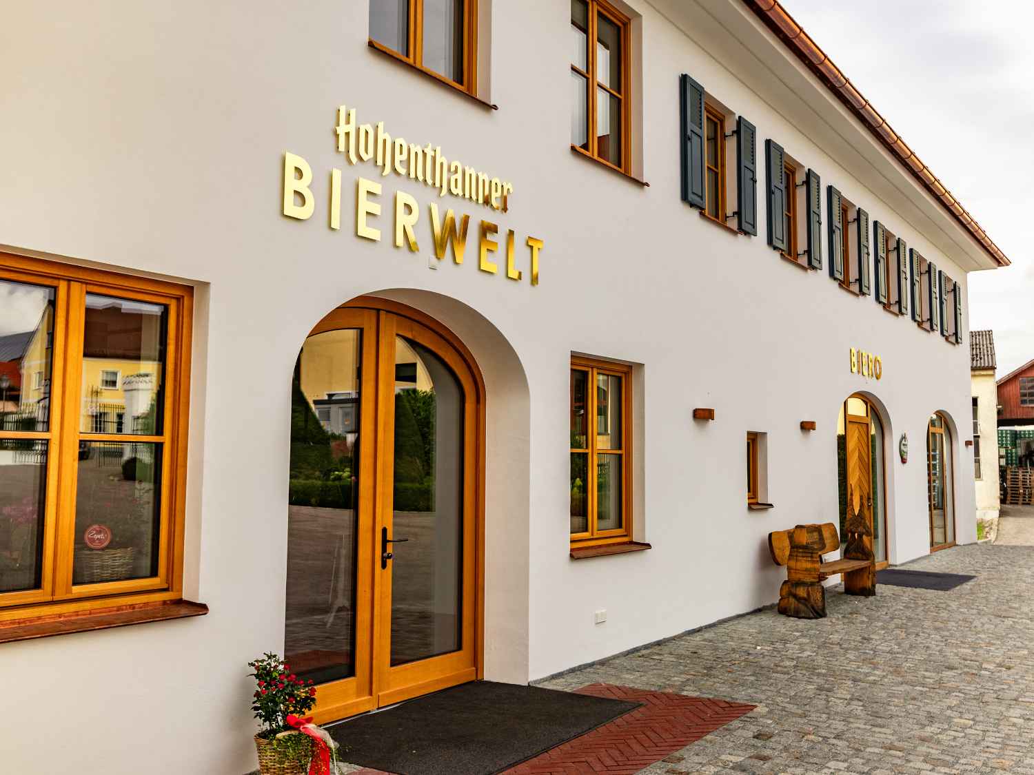 Fassade eines Gebäudes mit mehreren Fenstern und zwei Eingängen, über einem steht in großen Buchstaben 'Hohenthanner BIERWELT'.