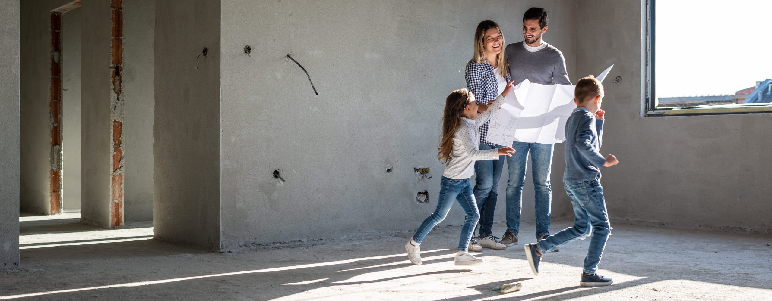 Junge Familie mit zwei Kindern auf Baustelle von Eigenheim